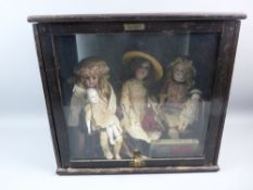 A CASED COLLECTION OF ANTIQUE BISQUE HEAD DOLLS, the three main seated with miniature dolls on their