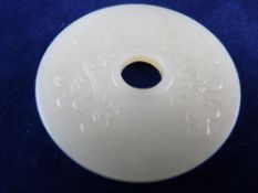 A CHINESE WHITE JADE CHANG YI ZI SUN DISC, the front with mythical beasts, the reverse with