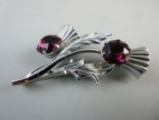 A LARGE WHITE METAL THISTLE BROOCH with two large round cut purple stones