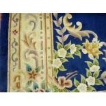 A LARGE BLUE GROUND WOOLLEN CARPET with wide cream border and central medallion of floral sprigs and