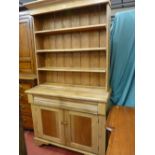 A VICTORIAN PINE DRESSER/BOOKCASE CONVERSION with inverted shaped cornice over four open shelves,