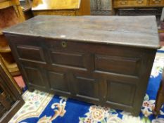 A PERIOD OAK LOOSE LID COFFER, the three plank top over inset panel sides and seven chamfered