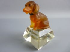 A FROSTED AMBER GLASS MODEL OF A SEATED DOG with inset eyes and a metal collar set upon a facet