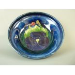 A MOORCROFT PANSY FOOTED BOWL, 11 cms diameter, decorated on a cobalt ground, inscribed to the