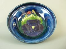 A MOORCROFT PANSY FOOTED BOWL, 11 cms diameter, decorated on a cobalt ground, inscribed to the