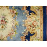 A 20th CENTURY WASHED WOOLLEN RECTANGULAR CARPET in tonal blues with floral design and tasseled