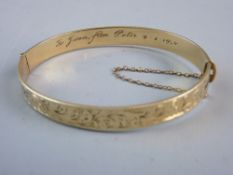 A NINE CARAT ROLLED GOLD HALF BRIGHT CUT BANGLE with presentation inscription 1958, 14.7 grms