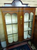 AN EDWARDIAN MAHOGANY DECORATED AND INLAID DISPLAY CABINET, the arched top back rail with urn and