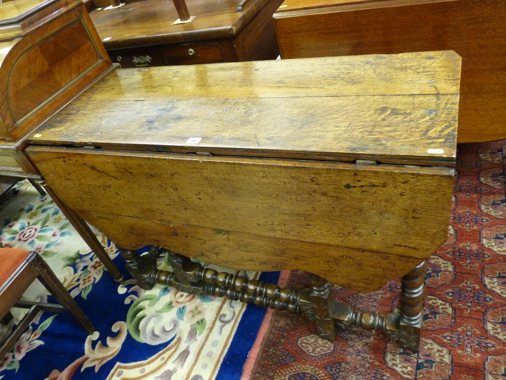 AN ANTIQUE OAK GATE LEG DINING TABLE with single flap and carved lower decoration with bobbin turned