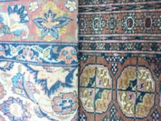 TWO EASTERN RED GROUND PATTERNED RUGS, a wide bordered example with central floral rectangular panel