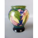 A MOORCROFT LEAF AND BERRY BALUSTER VASE, 15 cms high, in a tonal blue/green ground, marked to the