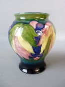 A MOORCROFT LEAF AND BERRY BALUSTER VASE, 15 cms high, in a tonal blue/green ground, marked to the