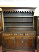 A MID 18th CENTURY WELSH OAK DRESSER, the three shelf wide boarded rack with inverted cornice over a