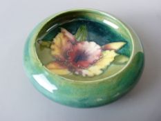 A MOORCROFT ORCHID BOWL, 11 cms diameter, decorated on a tonal green ground, impressed to the