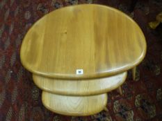 AN ERCOL LIGHT ELM NEST OF THREE PEBBLE TABLES, 40.5 cms high, 65 cms wide the largest