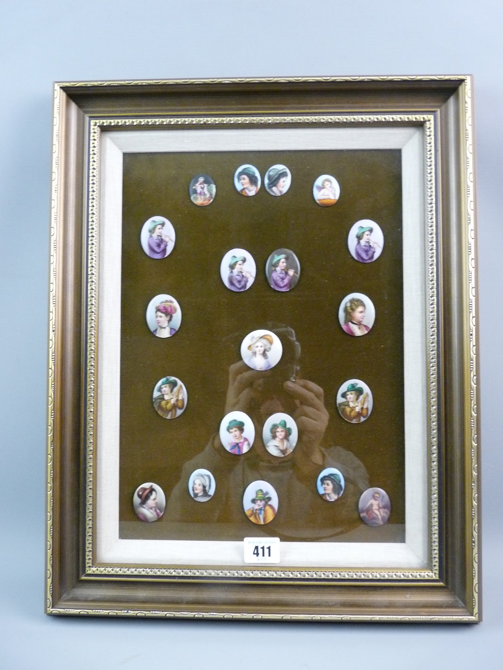 A FRAMED COLLECTION OF PORCELAIN CAMEOS, nineteen oval and one circular printed and painted