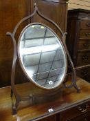 A REGENCY MAHOGANY DRESSING MIRROR of oval form in a shaped open stand with turned roundels and