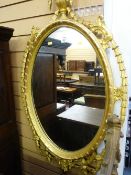 A REGENCY STYLE GILT DECORATED OVAL WALL MIRROR with flame topped urn finial and open swag and