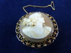 A NINE CARAT GOLD CIRCULAR CAMEO LADY BROOCH in a scrolled and bead frame, 10 grms