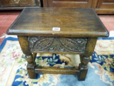 A REPRODUCTION JOINED OAK BOX SEAT FOOTSTOOL with carved front panel on turned and block supports,