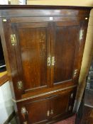 A GEORGE III OAK STANDING CORNER CUPBOARD of two large upper and two lower cupboard doors with brass