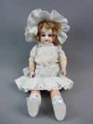 AN ANTIQUE ARMAND MARSEILLE BISQUE HEADED DOLL with fixed blue eyes, open mouth with teeth and