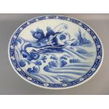 A LARGE ORIENTAL BLUE AND WHITE CHARGER decorated with a mythical dragon amongst swirling waves with