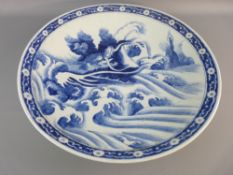 A LARGE ORIENTAL BLUE AND WHITE CHARGER decorated with a mythical dragon amongst swirling waves with