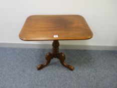 AN EDWARDIAN MAHOGANY RECTANGULAR TOPPED TABLE on a turned column tripod base, 56 cms high, 61 cms