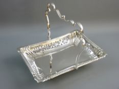 AN ELECTROPLATED BREAD BASKET with swing handle, pierced floral patterned sides, on ball and claw