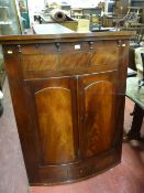 A VICTORIAN BOW FRONT HANGING WALL CUPBOARD, the top frieze with decorative moulding and crossbanded
