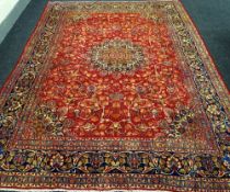 A LARGE OLD RED GROUND PERSIAN KASHAN CARPET with a shabaz medallion design, 388 x 294cms
