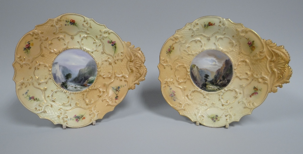 A PAIR OF ROYAL WORCESTER DISHES moulded with foliate handles and foliate borders featuring