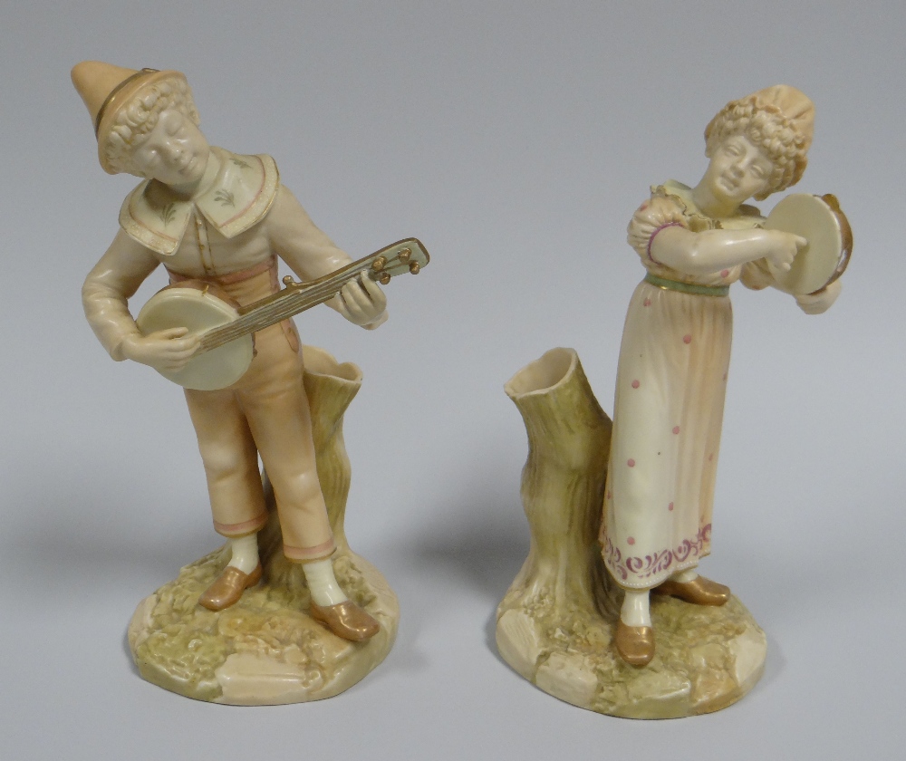 A PAIR OF ROYAL WORCESTER MUSICIAN SPILL-HOLDERS on naturalistic bases and stood against stumps