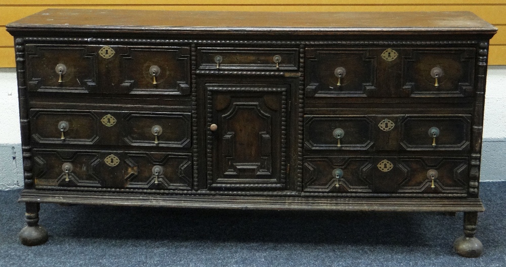 A JACOBEAN REVIVAL OAK SIDEBOARD with a centre single drawer and cupboard flanked by three drawers