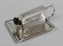 A SILVER TABLE CIGAR-CUTTER on a tray base, on bun-feet and with ring-handle, Chester, 1900, maker's
