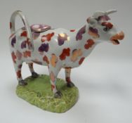 A SWANSEA POTTERY COW CREAMER with sponged lustre decoration, looped tail handle and standing on a