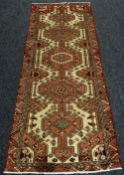 A WASHED RED GROUND PERSIAN RUNNER MEDALLION DESIGN, 290 x 110cms