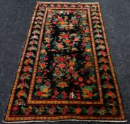 AN ANTIQUE PERSIAN CARPET of black ground with floral decoration, 233 x 130cms