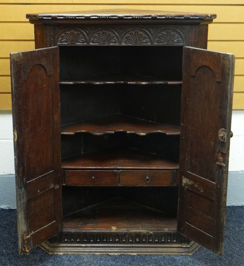 AN EARLY NINETEENTH CENTURY CARVED OAK CORNER CUPBOARD composed of two unglazed doors decorated with - Image 2 of 2