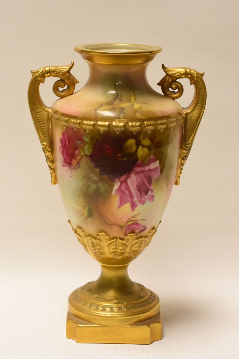 A ROYAL WORCESTER TWIN-HANDLED VASE raised on a chamfered square base and decorated with wild-roses,