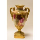 A ROYAL WORCESTER TWIN-HANDLED VASE raised on a chamfered square base and decorated with wild-roses,