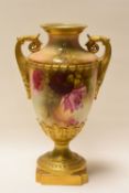 A ROYAL WORCESTER TWIN-HANDLED VASE raised on a chamfered square base and decorated with wild-roses,