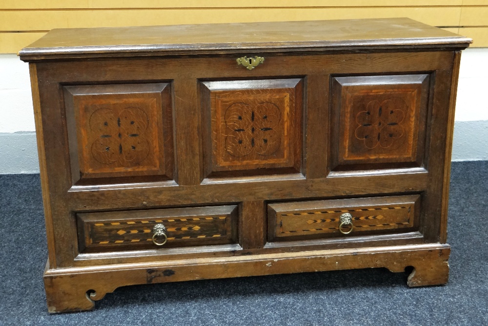 A WELSH INLAID OAK BLANKET CHEST of tri-panelled form and with a pair of base drawers bearing lion