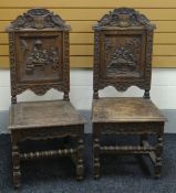 A PAIR OF CARVED OAK TAVERN SCENE CHAIRS with heraldic rails