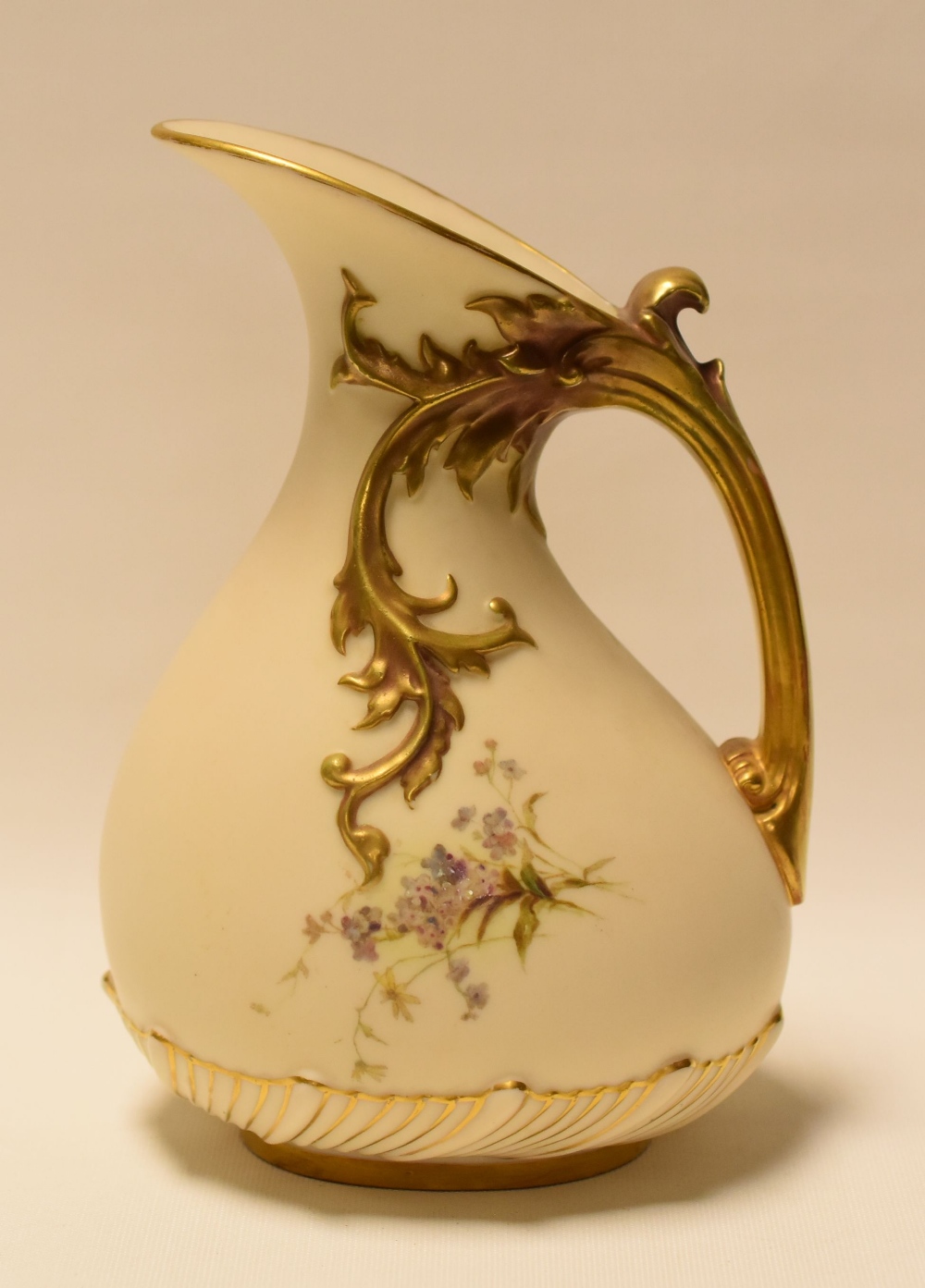 A ROYAL WORCESTER BLUSH IVORY JUG with gilded naturalistic handle and painted with wild-flowers,