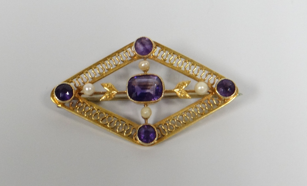 A 15CT GOLD AMETHYST & SEED PEARL BROOCH of hollow diamond form with filigree borders, 5.15gms