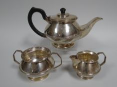 A THREE PART SILVER TEA-SET of circular based bulbous form with raised floral and leaf skirt,