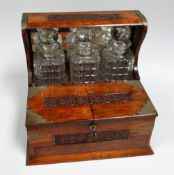 A CARVED OAK TANTALUS & CIGAR BOX with metallic mounts and a trio of hob-nail cut decanters with