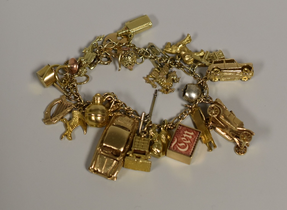 A 9CT GOLD CHARM BRACELET with approximately eighteen 9ct charms 60gms gross
